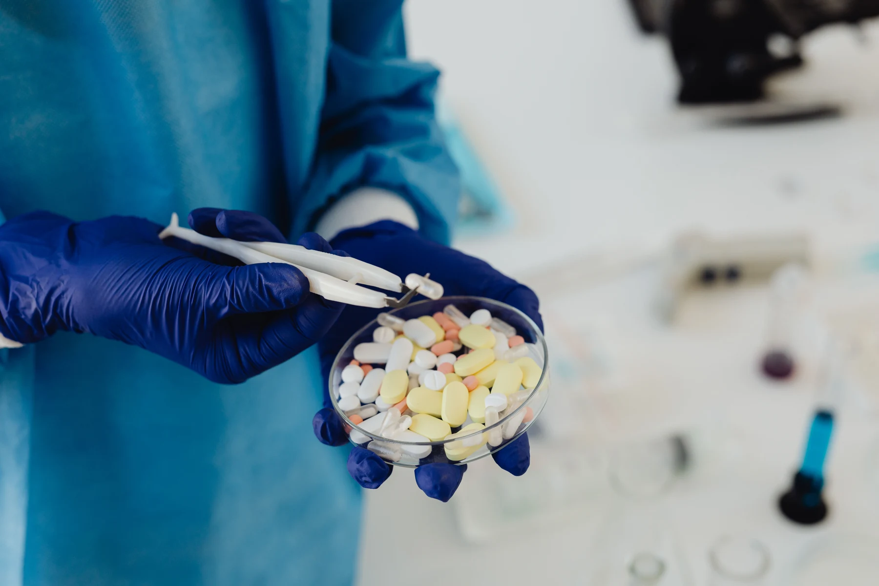 Gloved laboratory worker examining tablets and capsules